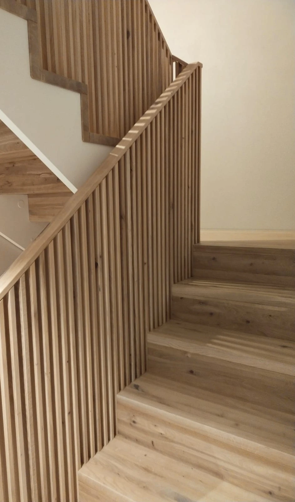 Betontreppe in Faltwerkoptik mit Wildeiche-Stufen und filigranem Holzstabgeländer 3