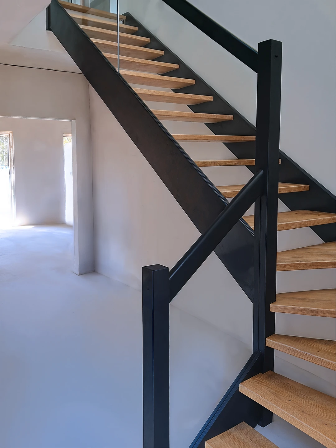 Holztreppe aus Eiche mit kontrastierenden, schwarzen Wangen und naturbelassenen Stufen  1