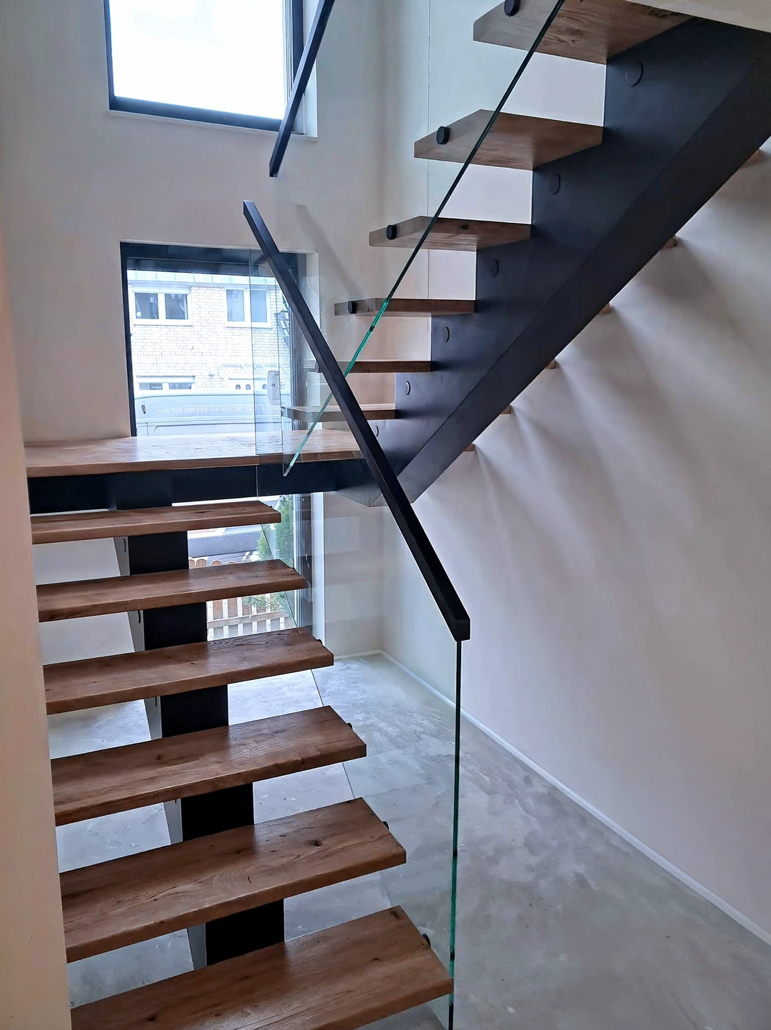 Moderne Mittelholmtreppe mit lackierten Holzstufen und schwarzem Mittelholm  1