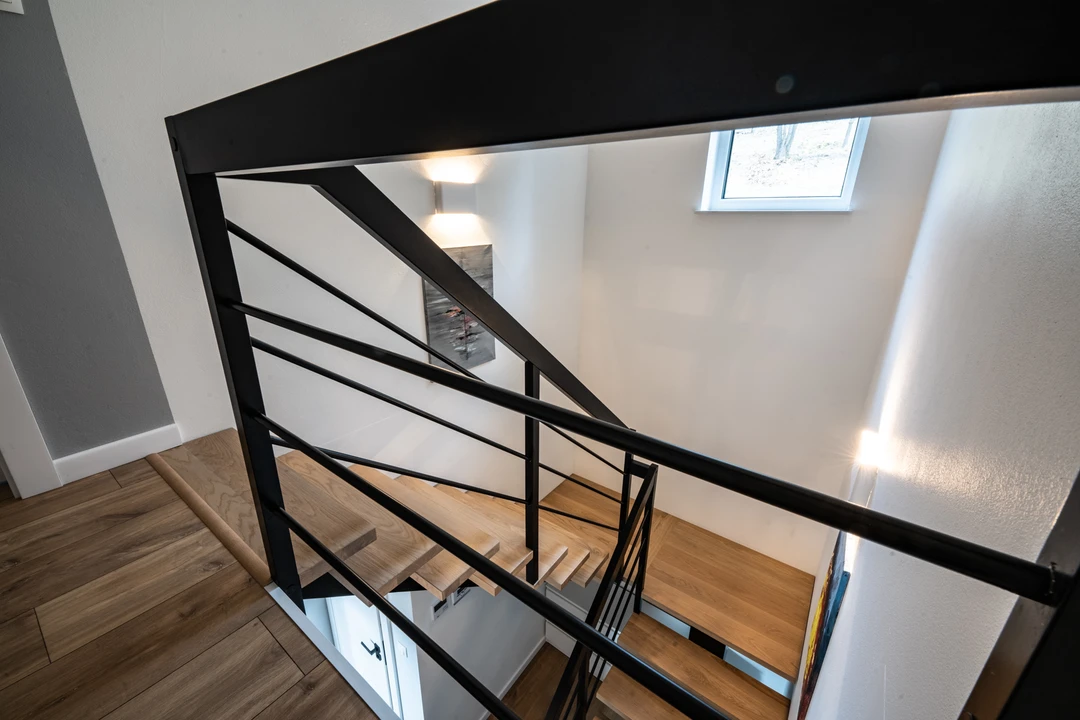 Moderne Mittelholmtreppe mit Relinggeländer, Holzstufen und schwarzer Konstruktion  5