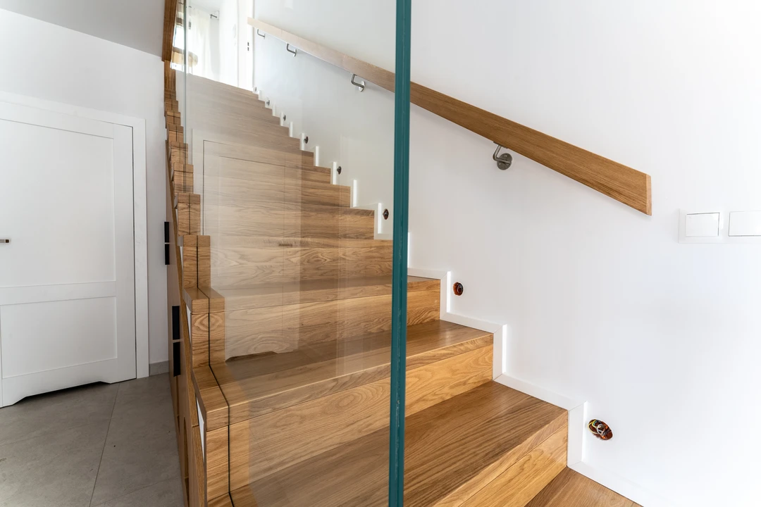 Moderne Stufen auf Beton (Treppe in Faltwerkoptik) mit eingelassenem Glasgeländer, Holzhandlauf und Holzstufen  2