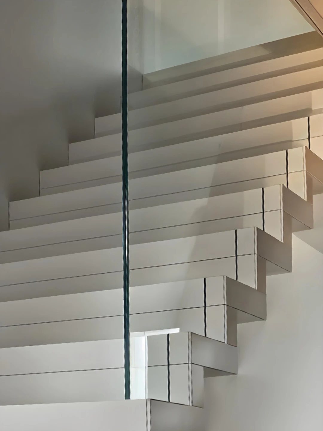 Moderne, weiß gestrichene Faltwerktreppe aus Buche mit eingelassenem Glasgeländer  1