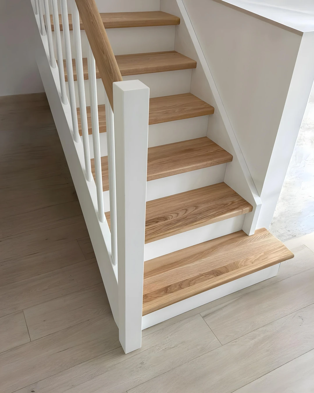 Wangentreppe mit weißen Wangen, Geländerstäben mit lackierten Stufen un Handlauf in Naturholzfarbe  0