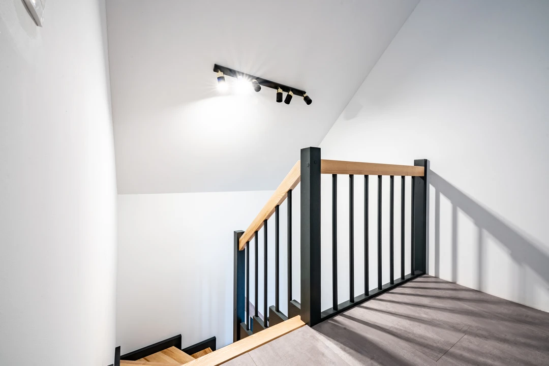 Zahnwangentreppe mit Geländerstäben, schwarzer Konstruktion sowie lackierten Stufen und Handlauf aus Esche in Naturholzfarbe  1