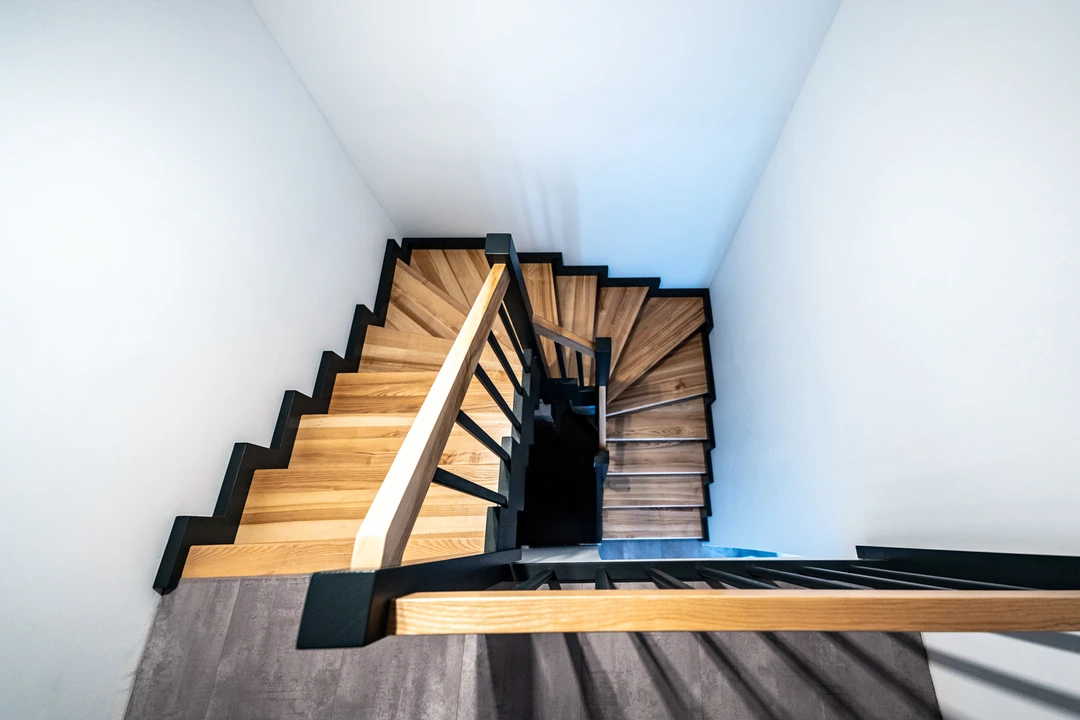 Zahnwangentreppe mit Geländerstäben, schwarzer Konstruktion sowie lackierten Stufen und Handlauf aus Esche in Naturholzfarbe  2