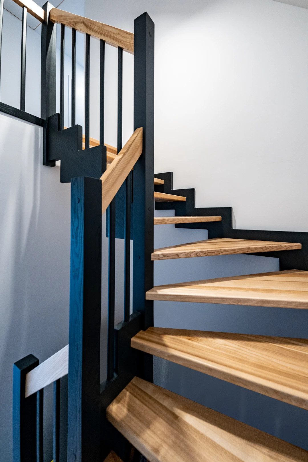 Zahnwangentreppe mit Geländerstäben, schwarzer Konstruktion sowie lackierten Stufen und Handlauf aus Esche in Naturholzfarbe  3