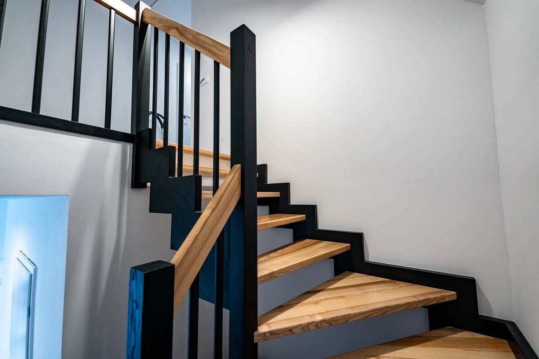 Zahnwangentreppe mit Geländerstäben, schwarzer Konstruktion sowie lackierten Stufen und Handlauf aus Esche in Naturholzfarbe  4