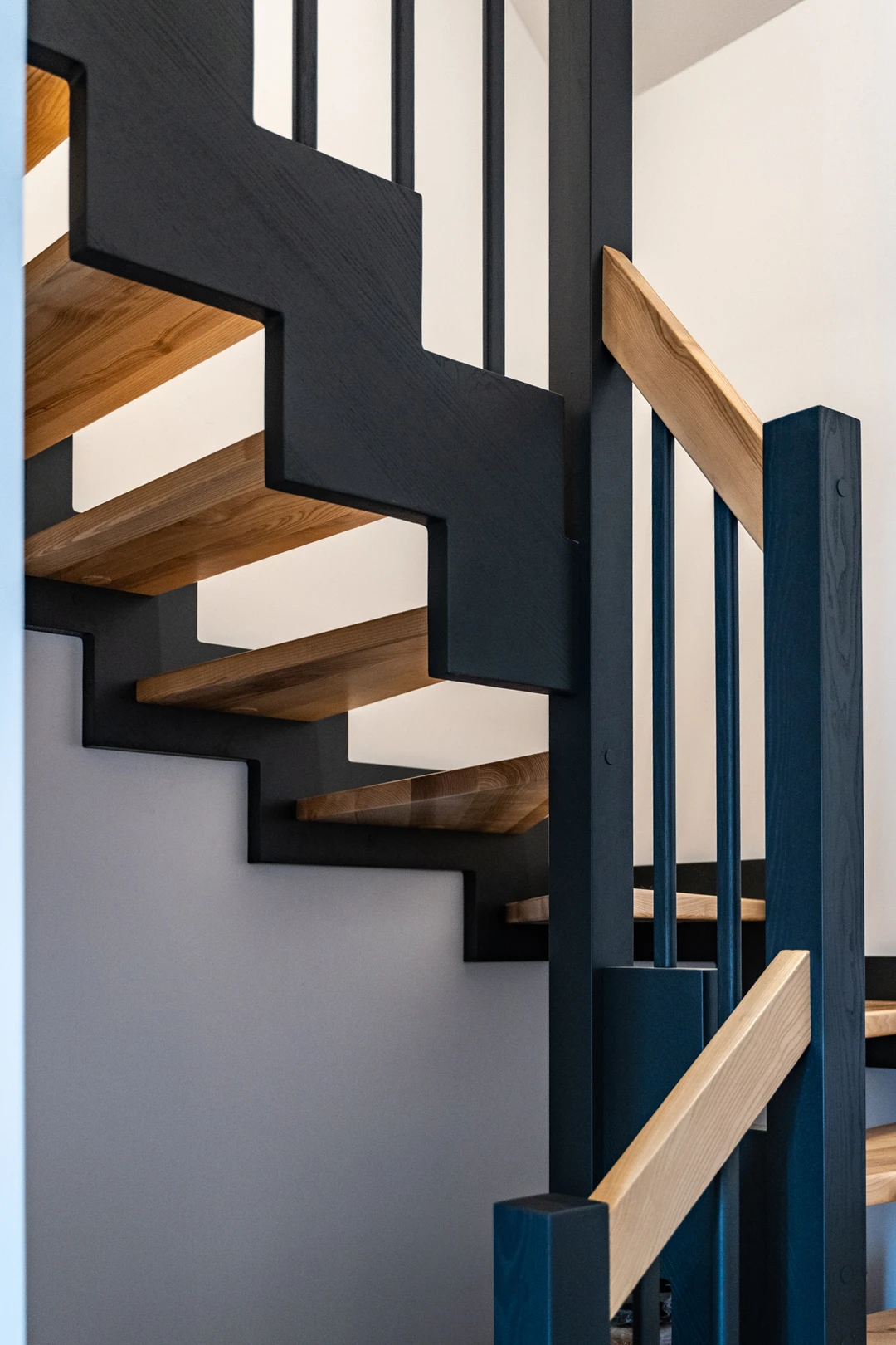 Zahnwangentreppe mit Geländerstäben, schwarzer Konstruktion sowie lackierten Stufen und Handlauf aus Esche in Naturholzfarbe  9